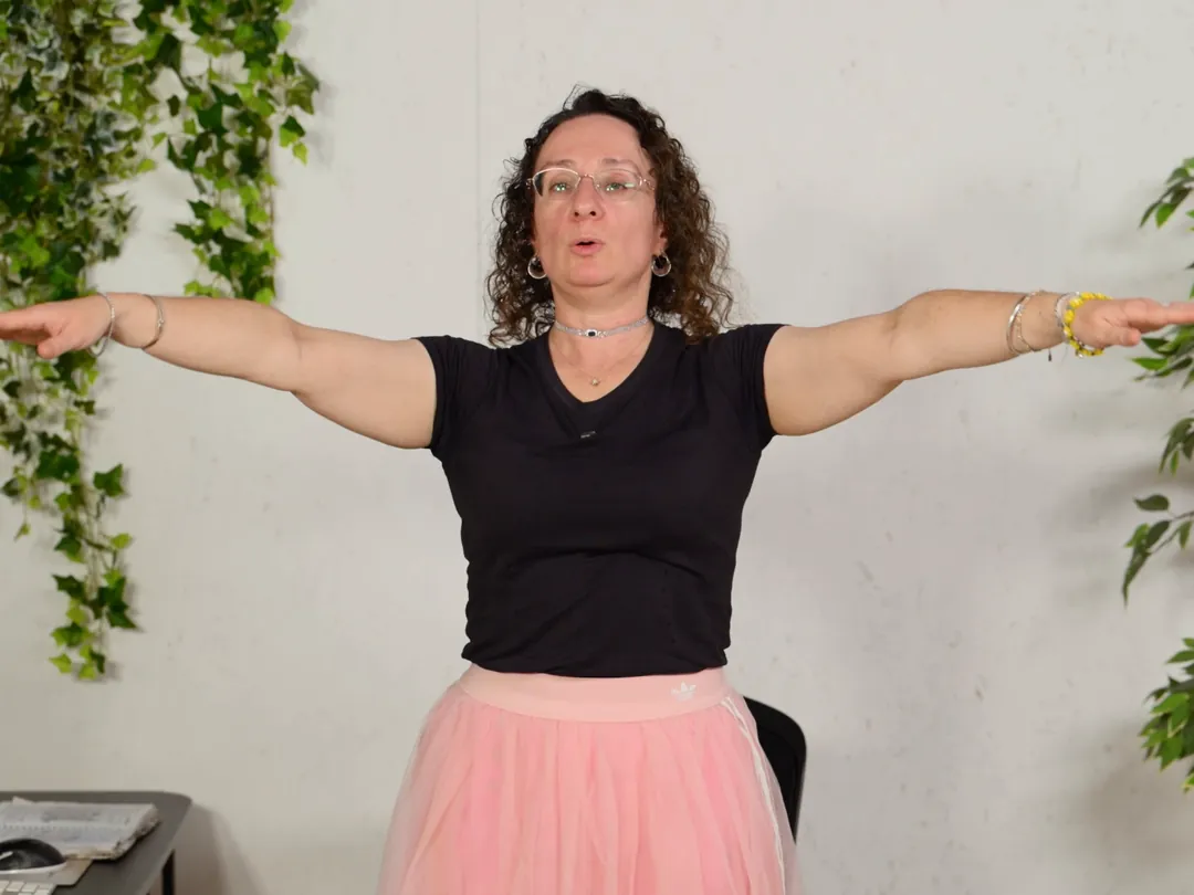 נטע מדגימה תרגיל כתפיים בעמידה
